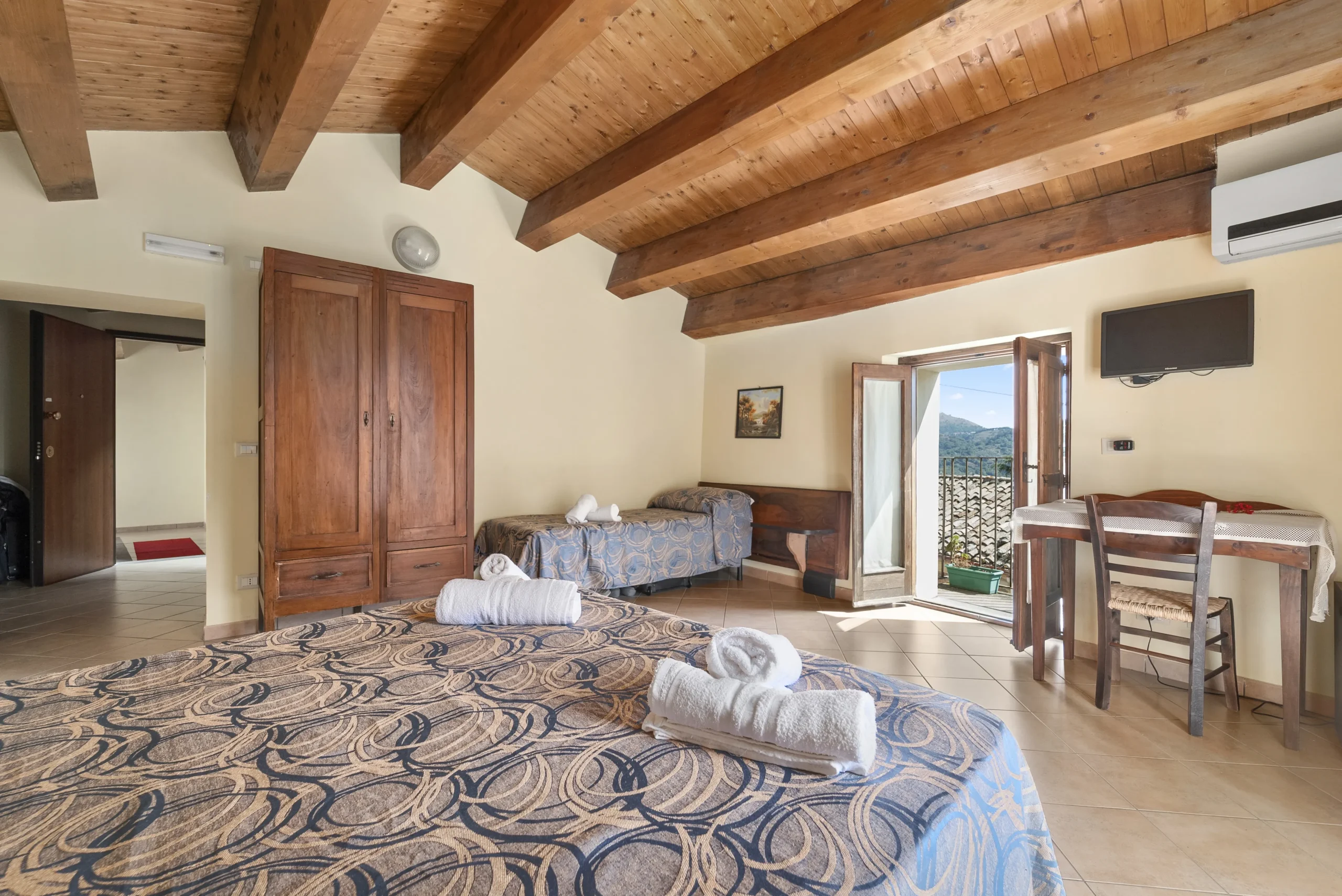 camera dell'albergo diffuso, due letti con sopra poggiati degli asciugamani accuratamente arrotolati, finestra aperta con il sole che entra