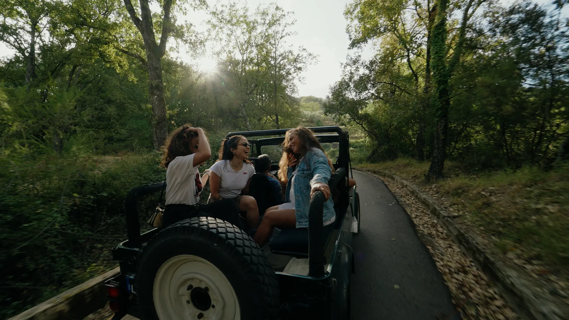 ragazze che ridono nel retro di una jeep su un sentiero